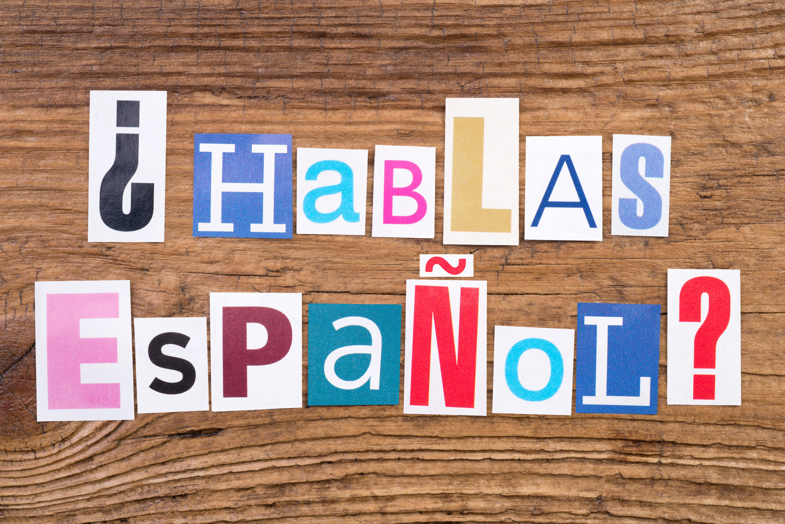 Question “Hablas Espanol?” in cut out magazine letters on wooden background